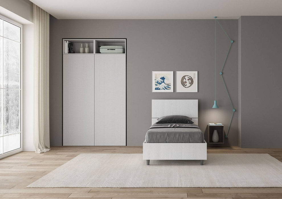 Letto singolo 80x200 Demas bianco in una stanza luminosa, con testata dritta e giroletto in nobilitato, stile minimalista e pratico.