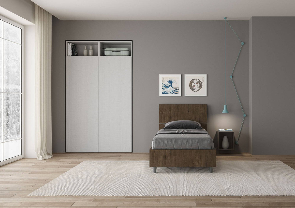 Letto singolo 80x200 Demas effetto legno scuro in una stanza luminosa, con testata dritta e giroletto in nobilitato, stile minimalista e pratico.