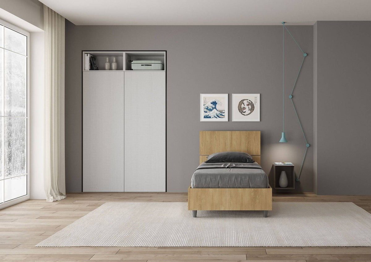 Letto singolo 80x200 Demas effetto legno chiaro in una stanza luminosa, con testata dritta e giroletto in nobilitato, stile minimalista e pratico.