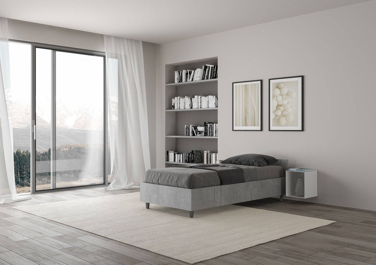 Letto singolo 80x200 Nuamo grigio in una camera moderna con ampie finestre e pavimento in legno chiaro.