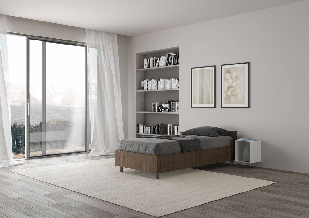 Letto singolo 80x200 Nuamo legno scuro in una camera moderna con ampie finestre e pavimento in legno chiaro.