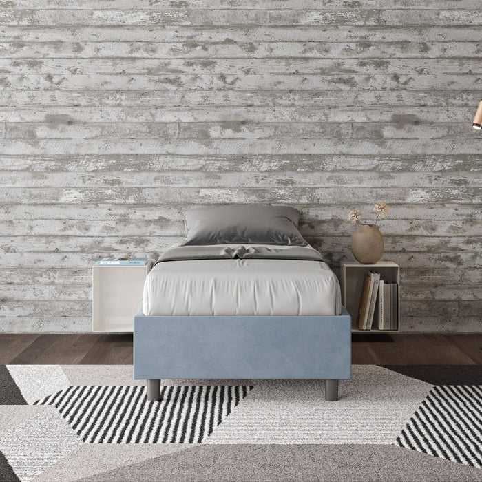 Letto singolo Azelia azzurro con contenitore, inserito in ambiente moderno con pareti effetto legno, ideale per camere fresche e luminose.