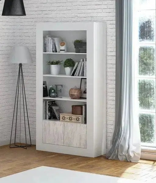 Colonna libreria moderna bianco antico Velho con 4 ripiani e 2 ante inferiori, decorata con piante e accessori, in un soggiorno elegante.