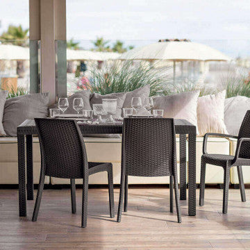 Set di Poltrone Indiana marroni in wicker con tavolo in un ambiente esterno. Ideale per arredare terrazze e giardini.