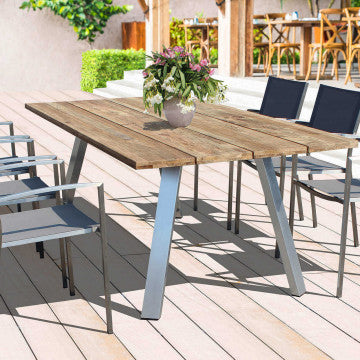 Poltrona Florida in acciaio inox e textilene grigio inserita in un contesto outdoor con tavolo in legno, ideale per arredamento da giardino.