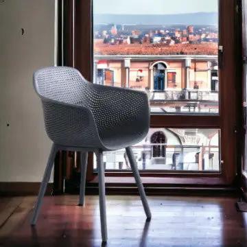 Poltrona Vannes in polipropilene taupe posizionata in un interno con vista panoramica, ideale per arredamento moderno.
