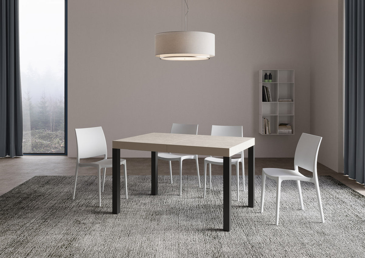 Tavolo allungabile Everyday telaio Antracite in soggiorno luminoso, abbinato a sedie bianche e tappeto grigio, stile essenziale e versatile.