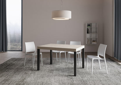 Tavolo allungabile Everyday telaio Antracite in soggiorno luminoso, abbinato a sedie bianche e tappeto grigio, stile essenziale e versatile.