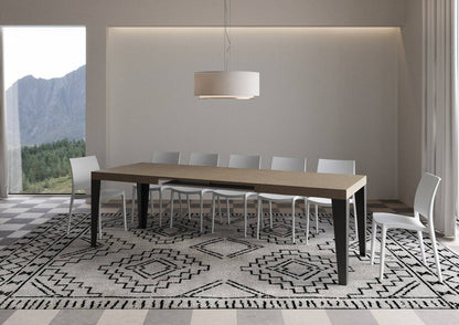 Tavolo Flame allungabile con gambe antracite, completamente esteso per 18 persone in ambiente elegante con tappeto geometrico.