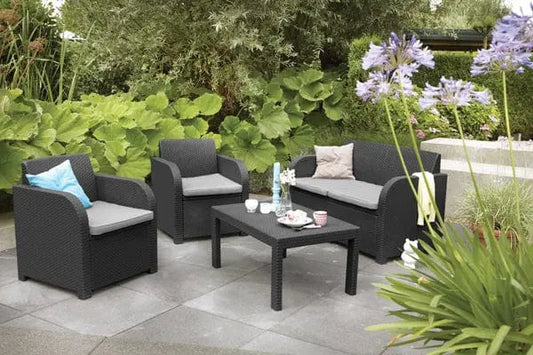 Salotto Carolina graphite con cuscini grigi da esterno, composto da divano, due poltrone e tavolino, su patio in giardino moderno