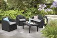 Salotto Carolina graphite con cuscini grigi da esterno, composto da divano, due poltrone e tavolino, su patio in giardino moderno